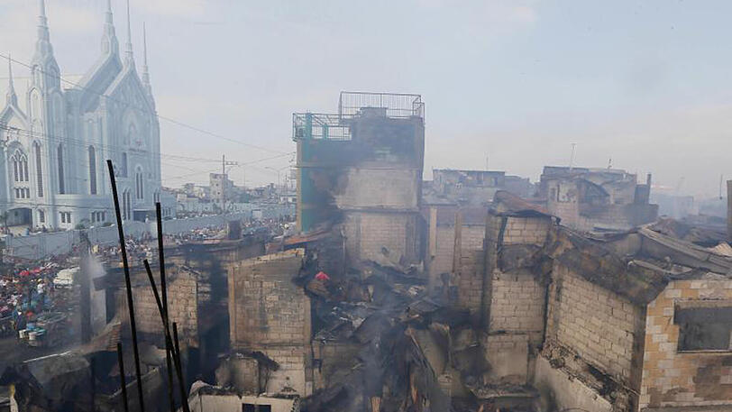 Opfer des Großbrandes durchsuchen in Manila durch die Flammen zerstörte Unterkünfte.