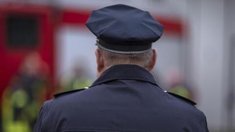 Ein Polizist steht vor einem Feuerwehrwagen. Foto: Jens Büttner/Archivbild