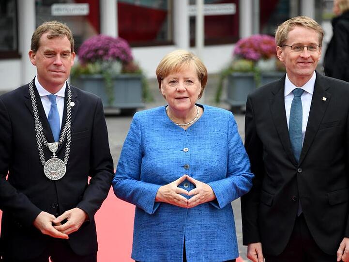 Ulf Kämpfer, Kieler Oberbürgermeister, Bundeskanzlerin Merkel und Daniel Günther, Ministerpräsident von Schleswig-Holstein, stehen im Rahmen der zentralen Feier zum Tag der Deutschen Einheit zusammen.