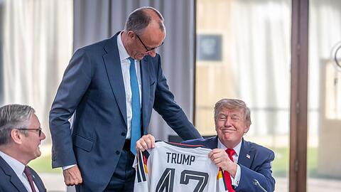 Helfen kleine Aufmerksamkeiten? Zum Geburtstag bekam Trump von Kanzler Merz ein Fu&szlig;ball-Trikot geschenkt. (Archivbild)