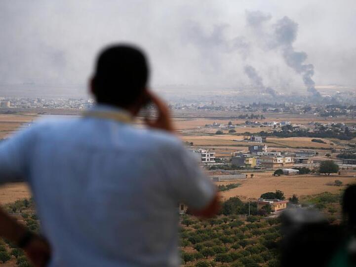 Ein Journalist beobachtet den Rauch, der nach einem türkischen Bombardement über der syrischen Stadt Ras al-Ain aufsteigt.