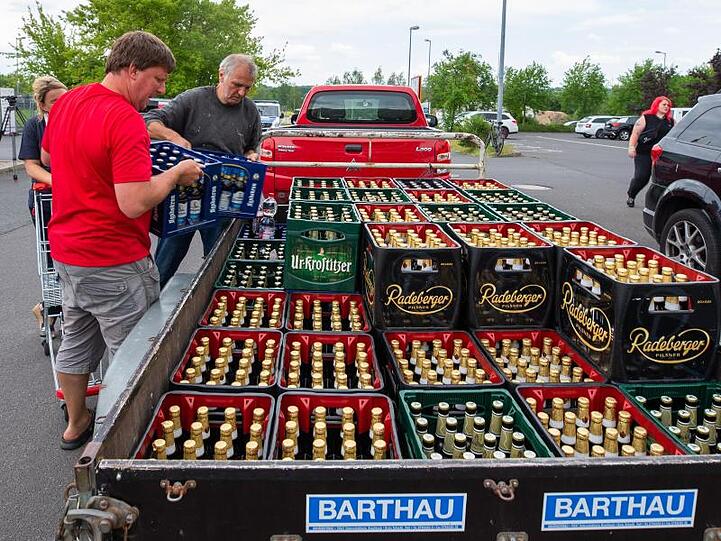 Eine Frau und zwei Männer laden Bierkästen in der Nähe eines örtlichen Supermarktes auf einen Anhänger. Das ganze Bier des Supermarktes wurde in einer Aktion von Bürgern und des IBZ (Internationalen Begegnungszentrum des Kloster Sankt Marienthal) aufgekauft.