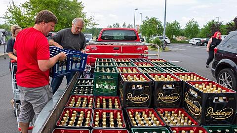 Eine Frau und zwei Männer laden Bierkästen in der Nähe eines örtlichen Supermarktes auf einen Anhänger. Das ganze Bier des Supermarktes wurde in einer Aktion von Bürgern und des IBZ (Internationalen Begegnungszentrum des Kloster Sankt Marienthal) aufgekauft.