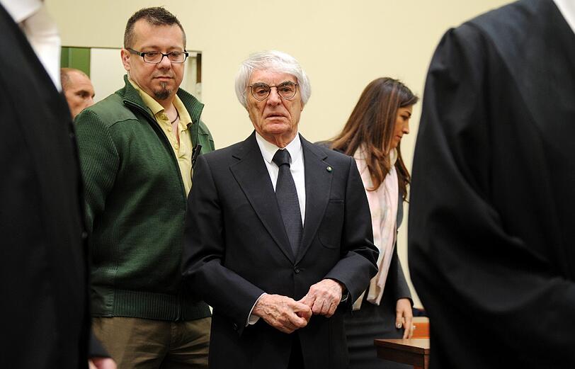 Formel-1-Chef Bernie Ecclestone (M) kommt am 02.05.2014 im Landgericht München I vor Prozessbeginn in den Verhandlungssaal, hinter ihm geht seine Frau Fabiana Flosi (r).