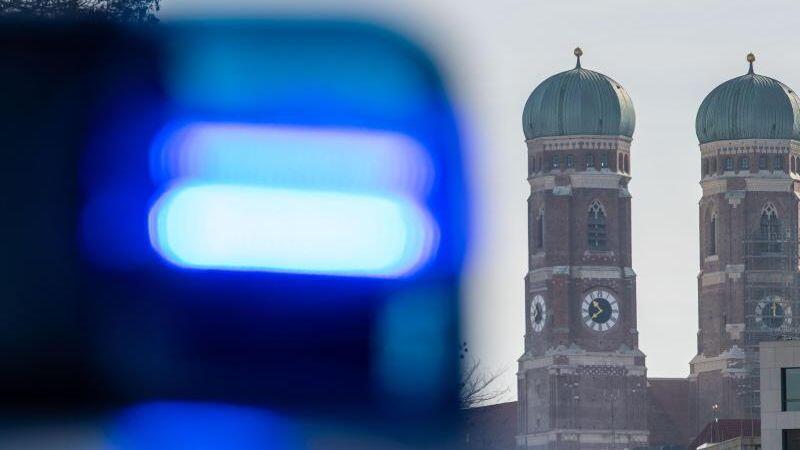 Ein Blaulicht einer Polizeistreife ist vor den Türmen der Frauenkirche zu sehen. Foto: Lino Mirgeler/dpa/Archivbild