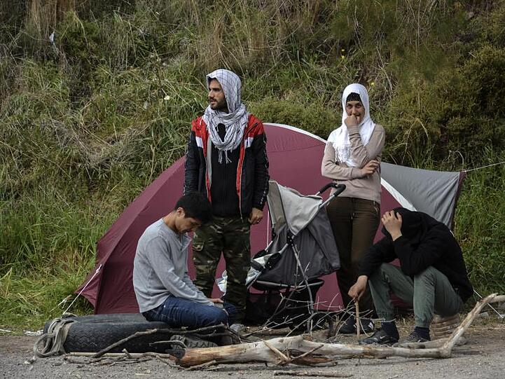 Migranten ruhen vor einem Zelt im Dorf Petra auf der nordöstlichen Ägäisinsel Lesbos in Griechenland.