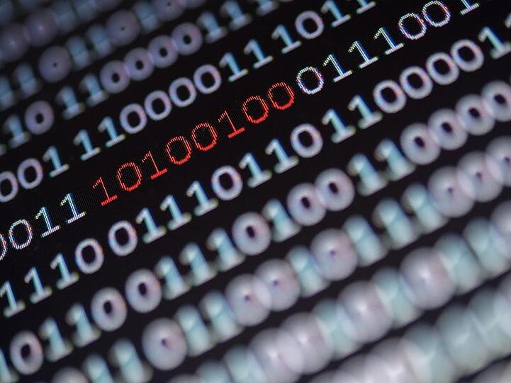 Ein Binärcode, von dem ein Segment rot eingefärbt ist, steht auf einem Bildschirm. Foto: Sebastian Gollnow/Archiv