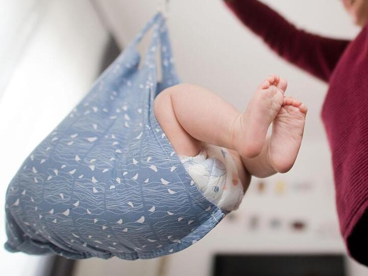 Eine Hebamme wiegt ein Baby. Foto: Julian Stratenschulte/dpa/Symbolbild