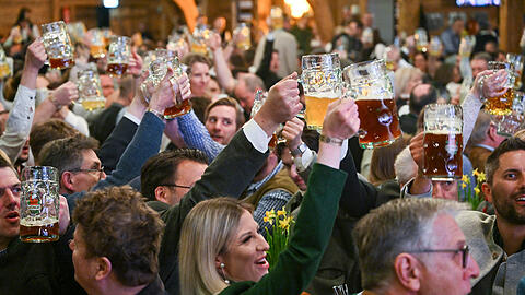 Gäste erheben beim Starkbieranstich der Giesinger Brauerei auf dem Firmengelände die Bierkrüge.