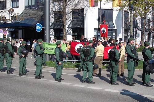 Die Internationale Apfelfraktion hinter der Polizeiabsperrung - linker Spott gegen braune Gesinnung.