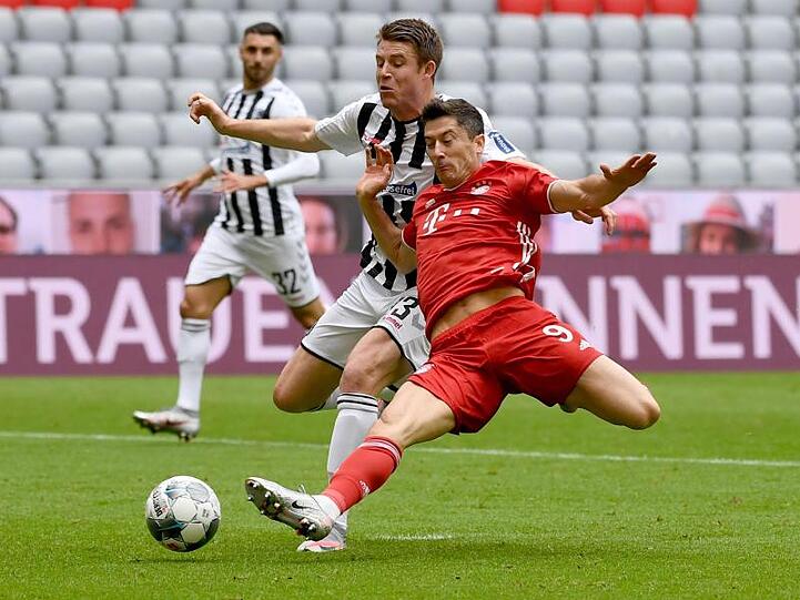 Freiburgs Dominique Heintz (M) und Münchens Robert Lewandowski (r) kämpfen um den Ball. Foto: Sven Hoppe/dpa-Pool/dpa