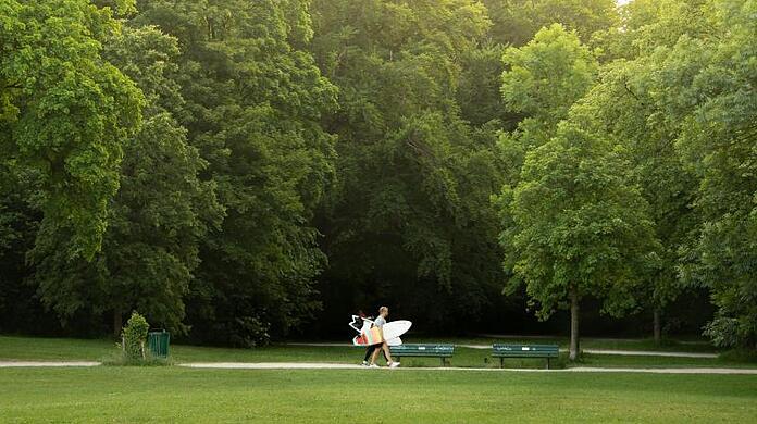 Diese beiden jungen Männer sind mit ihren Surfboards auf dem Weg zum Eisbach im Englischen Garten von München.