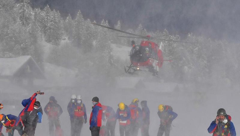 Ein Helikopter landet hinter Helfern der Bergrettung.