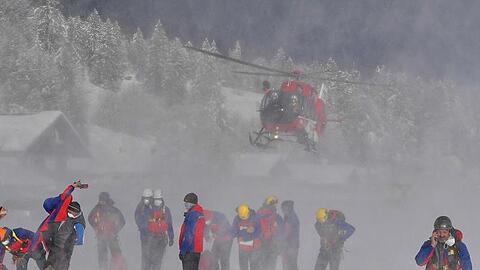Ein Helikopter landet hinter Helfern der Bergrettung.