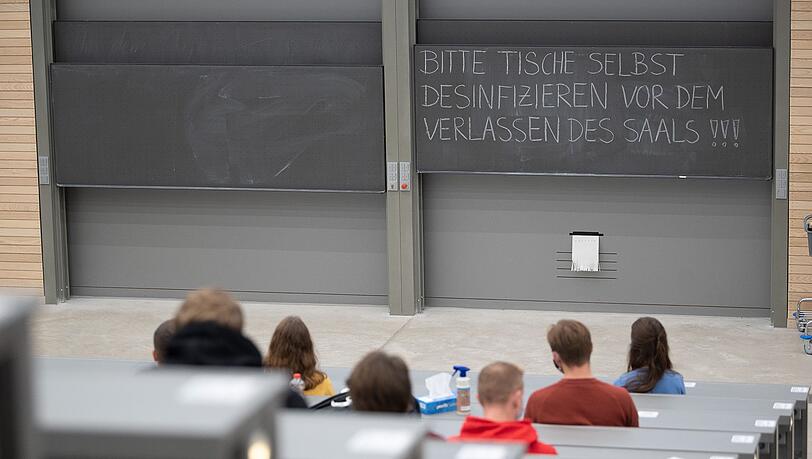 Studierende mit Mund- und Nasenmaske sitzen in einem Hörsaal.