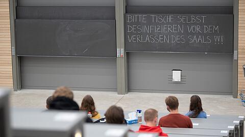 Studierende mit Mund- und Nasenmaske sitzen in einem Hörsaal.