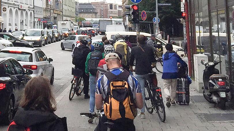 Zahlreiche Radfahrer warten im dichten Münchner Berufsverkehr - so wie hier vor der roten Ampel.
