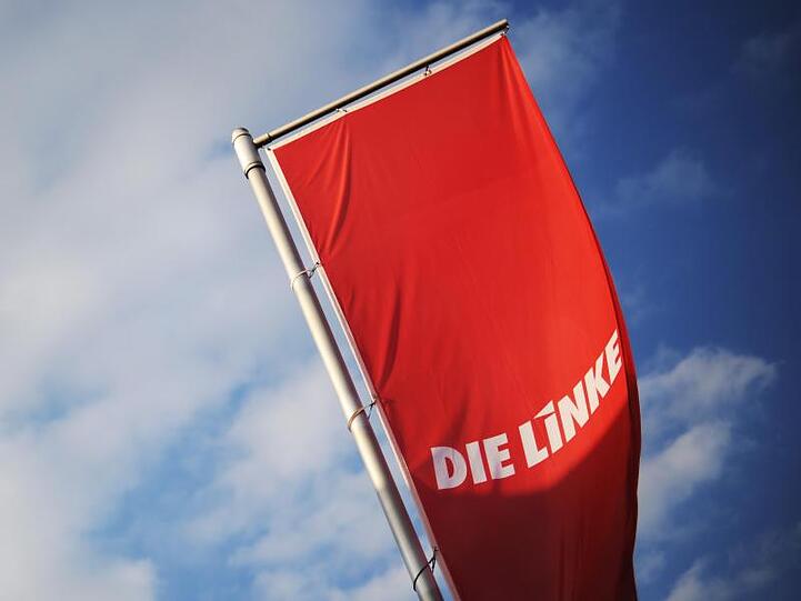 Fahnen der Linken vor strahlend blauem Himmel. Foto: Julian Stratenschulte/Archiv