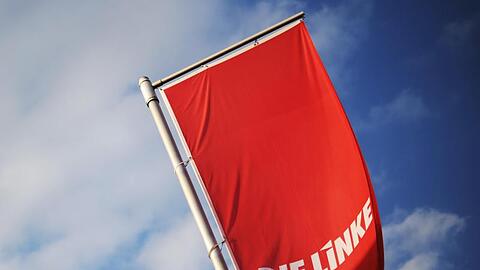 Fahnen der Linken vor strahlend blauem Himmel. Foto: Julian Stratenschulte/Archiv