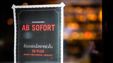 Ein Plakat weist Gäste am Eingang eines Restaurants in Stuttgart auf die neue 2G Plus Regel hin.