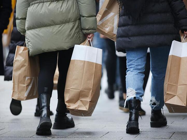 Frauen tragen Einkaufstüten über die Königsallee in Düsseldorf.