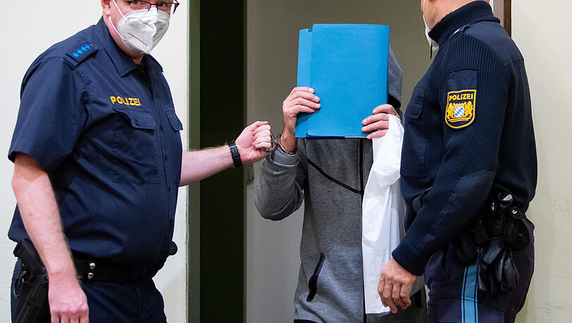 Der wegen Mordes durch Unterlassen angeklagte Mann (Mitte) wird in den Gerichtssaal geführt.