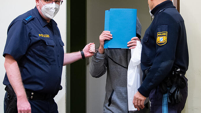 Der wegen Mordes durch Unterlassen angeklagte Mann (Mitte) wird in den Gerichtssaal geführt.