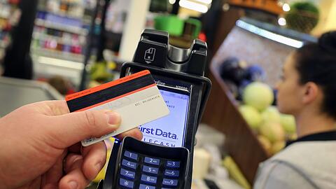 Eine EC-Karte wird an den Bezahl-Terminal an der Kasse eines Supermarktes gehalten.