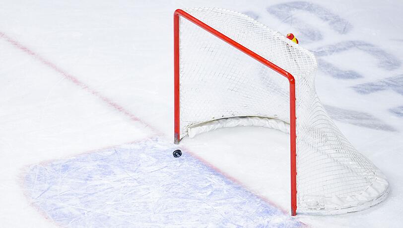 Ein Puck fliegt in ein leeres Eishockey-Tor.
