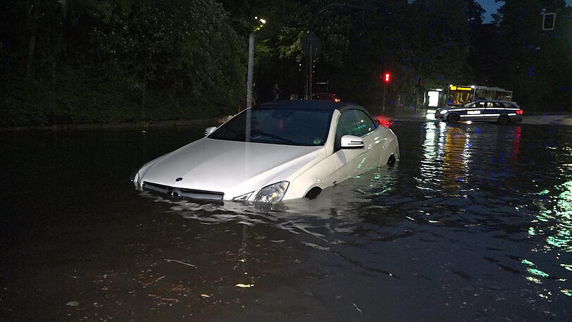 Ein von Wassermassen überflutetes Auto steckt am Freitagabend  an der S-Bahn-Unterführung in der Bovestraße in Hamburg fest.