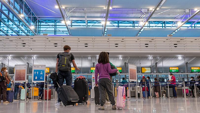Passagiere stehen am Münchner Flughafen an einem Check-iIn-Schalter.