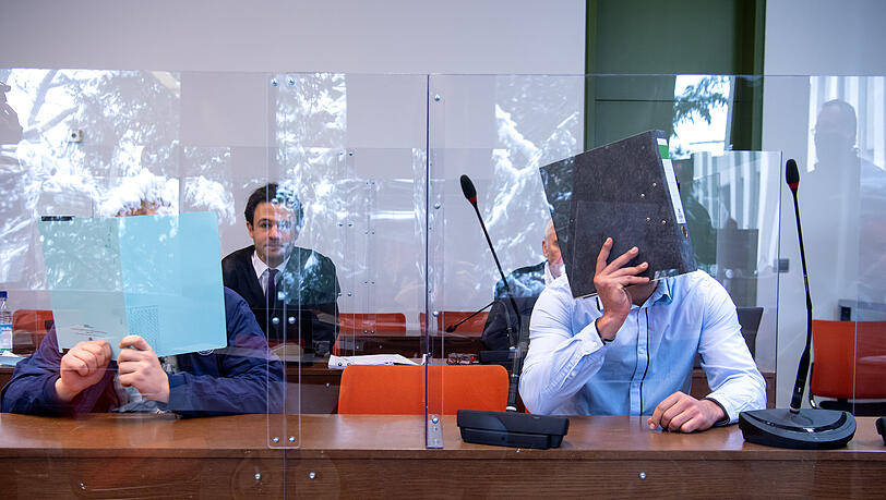 Zwei wegen gewerbs- und bandenmäßigen Betrugs und Bandendiebstahls angeklagte Männer sitzen vor Prozessbeginn im Gerichtssaal.