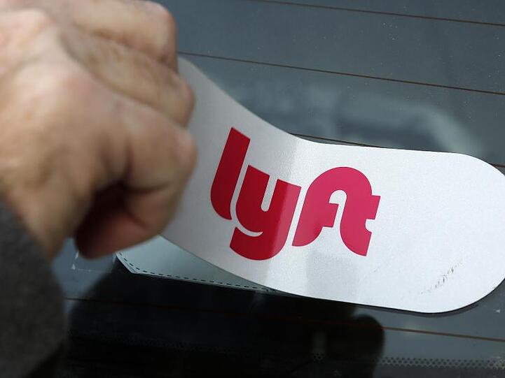 Ein Mann bringt das Logo des Mitfahrdienstes Lyft an einem Auto an.