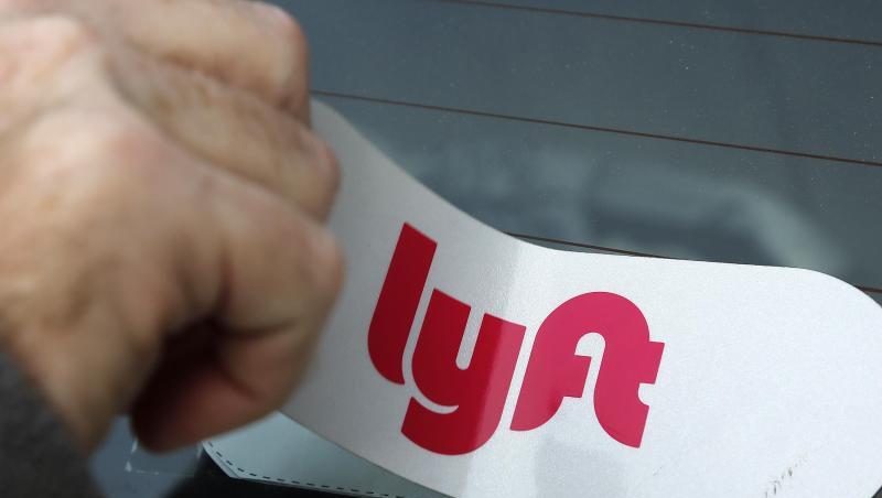 Ein Mann bringt das Logo des Mitfahrdienstes Lyft an einem Auto an. Ein Mann bringt das Logo des Mitfahrdienstes Lyft an einem Auto an.