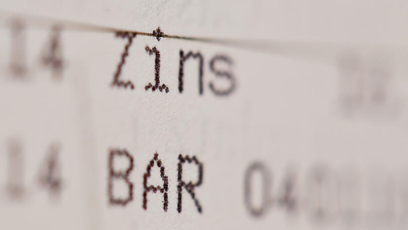 Die Einträge "Zins" und "Bar" in einem Sparbuch. Für den millionenschweren Entschädigungsfonds für Denkmalsanierungen musste Bayern Negativzinsen an Banken bezahlen.