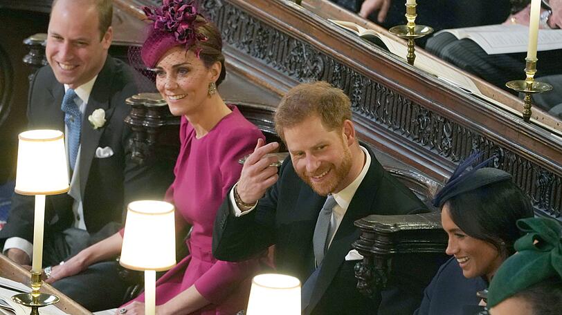 Prinz William und Herzogin Kate sitzen neben Prinz Harry und Herzogin Meghan während der Hochzeit von Prinzessin Eugenie und Jack Brooksbank in der St.-Georges-Kapelle von Schloss Windsor. Die Farbe Magenta steht Kate hervorragend.