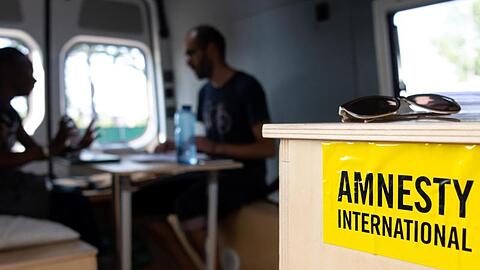 Aydin Alinejad vom Münchner Flüchtlingsrat unterhält sich in einem "Infobus für Flüchtlinge" mit einer Frau aus Uganda. Foto: Sven Hoppe