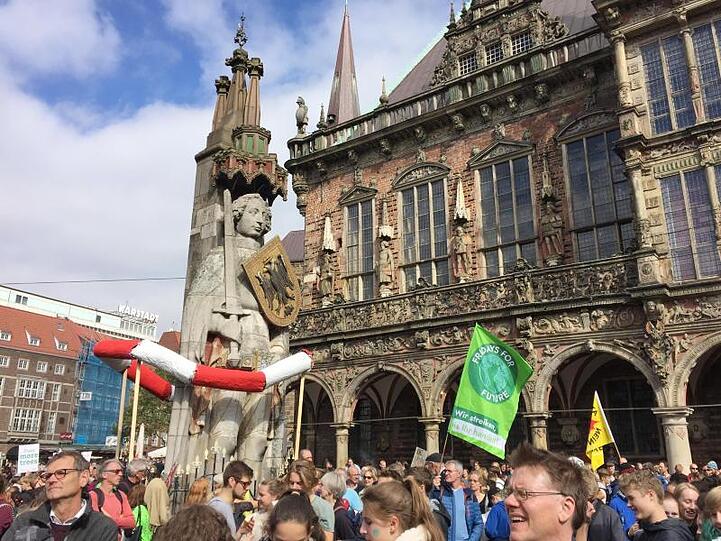 Demonstranten stehen vor dem historischen Rathaus und dem Roland in Bremen.