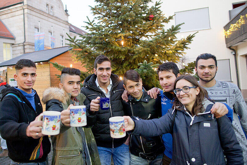 Die Leiterin der Wohngruppe der Caritas für jugendliche Flüchtlinge in Schnaittach, Sofia Wunner, trinkt mit jungen Flüchtlingen der Einrichtung auf dem Weihnachtsmarkt in Schnaittach Kinderpunsch.