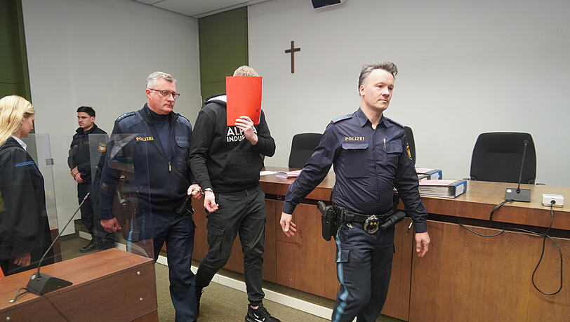 Der Angeklagte wird von Polizeibeamten in den Gerichtssaal geführt. Der Angeklagte wird von Polizeibeamten in den Gerichtssaal geführt.