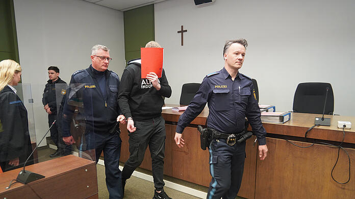 Der Angeklagte wird von Polizeibeamten in den Gerichtssaal geführt.