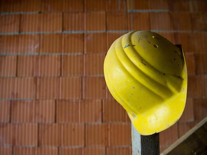 Ein Bauhelm hängt auf einer Baustelle. Foto: Daniel Bockwoldt/dpa/Symbolbild