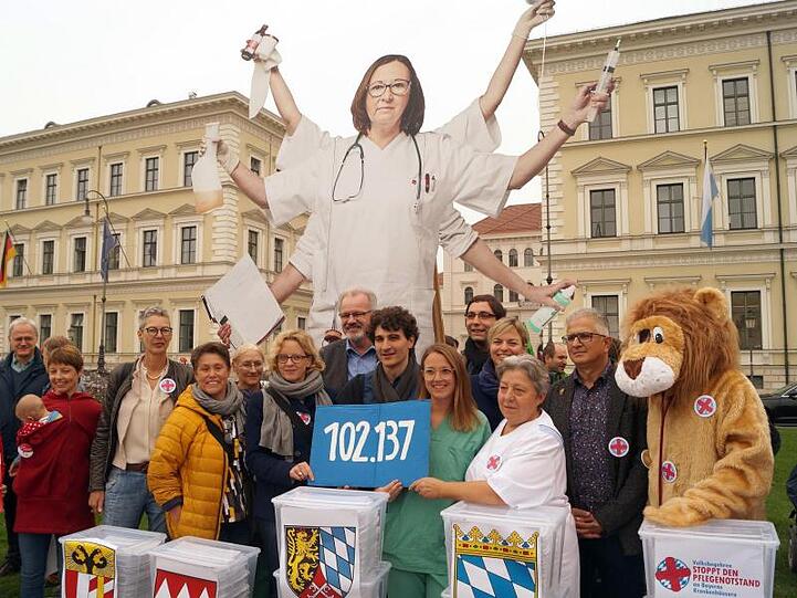 Natascha Kohnen (SPD) , Ates Gürpinar (Linke) und Pflegekräfte halten ein Schild mit der Zahl 102 137. Foto: Stefan Jagel/Archivbild