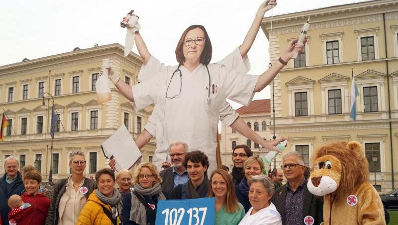 Natascha Kohnen (SPD) , Ates Gürpinar (Linke) und Pflegekräfte halten ein Schild mit der Zahl 102 137. Foto: Stefan Jagel/Archivbild Natascha Kohnen (SPD) , Ates Gürpinar (Linke) und Pflegekräfte halten ein Schild mit der Zahl 102 137. Foto: Stefan Jagel/Archivbild