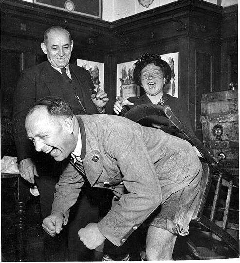 Beppo Brem testet 1950 mit seiner Stuhlprobe, ob das Starkbier taugt. Oberbürgermeister Thomas Wimmer und Liesl Karlstadt sind vom Ergebnis begeistert.