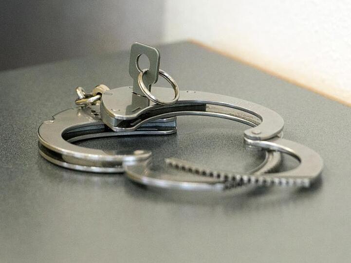 Handschellen liegen auf einem Tisch. Foto: Armin Weigel/dpa