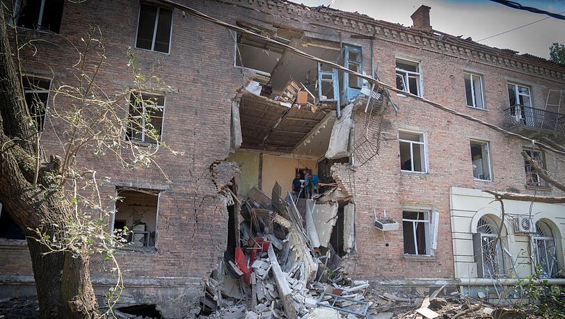 Menschen bergen einige ihrer Habseligkeiten aus einem Gebäude in Bachmut, das bei einem russischen Raketenangriff im Stadtzentrum Anfang Juli beschädigt wurde.