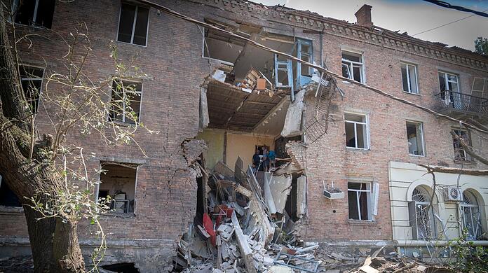 Menschen bergen einige ihrer Habseligkeiten aus einem Gebäude in Bachmut, das bei einem russischen Raketenangriff im Stadtzentrum Anfang Juli beschädigt wurde.