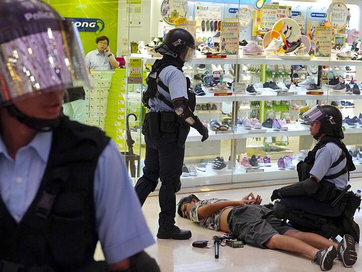 Polizisten nehmen vor einem Schuhladen einen Mann fest.