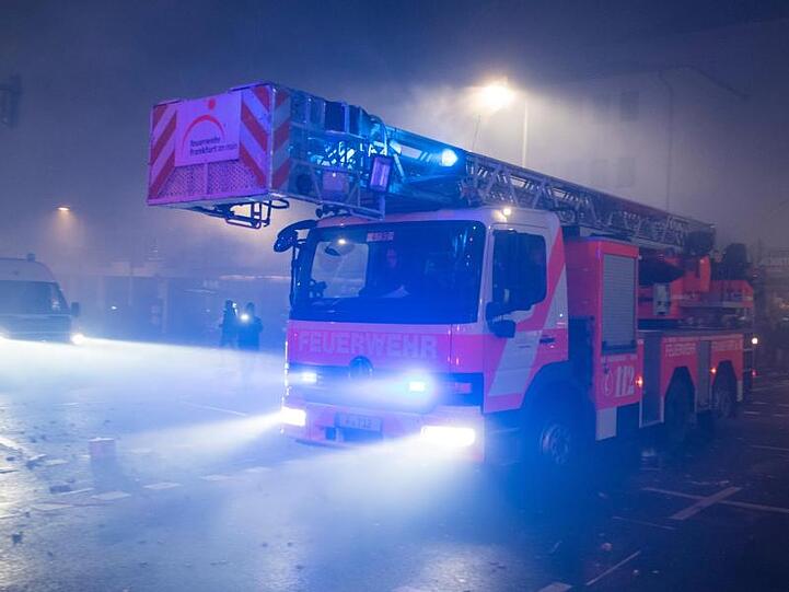 Ein Einsatzfahrzeug der Feuerwehr mit Drehleiter bahnt sich in Frankfurt am Main den Weg durch die Straßen.